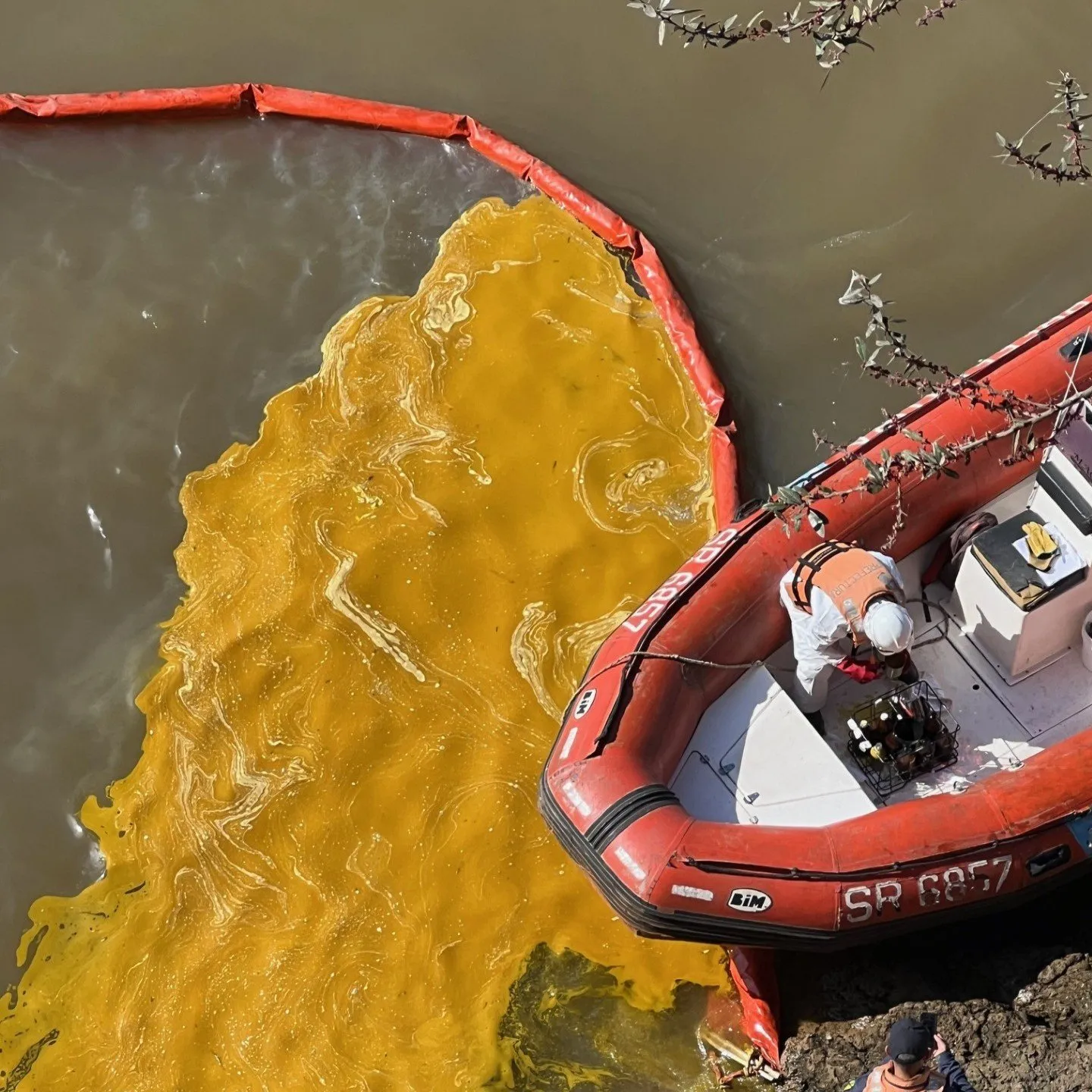 Barrera de contención desplegada sobre un derrame en el agua